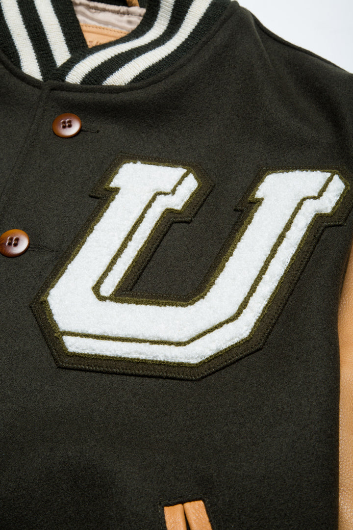 UNINTERRUPTED ALL STAR VARSITY JACKET LODEN GREEN (4458685071440) - close up of the "U" patch